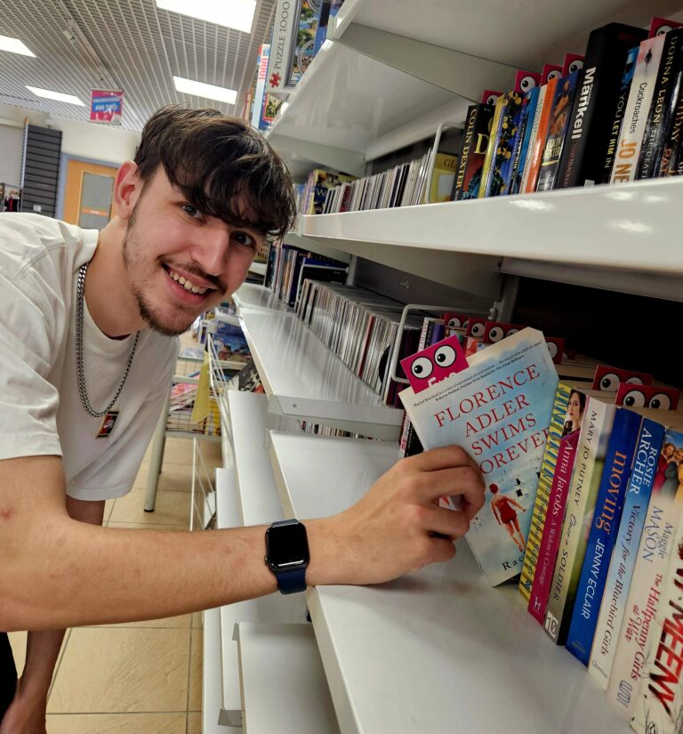 This shows Jarad, a young man from our Sedgley shop pulling a book from our bookshelf.